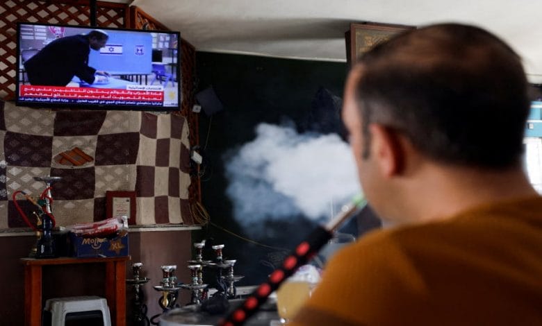 فلسطيني يدخن الأرجيلة بينما يشاهد الأخبار عن الانتخابات الإسرائيلية